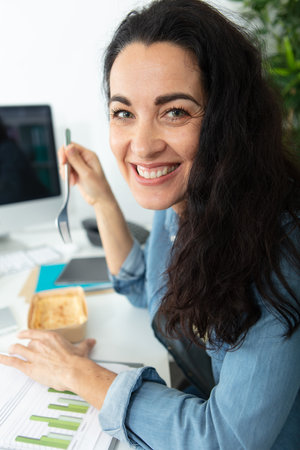 beautiful woman eating lunch in officeの写真素材