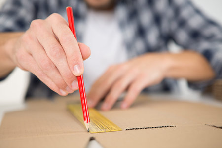 packaging designer drawing a line on cardboard