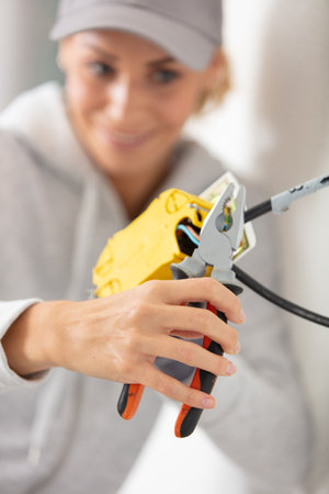 young tradeswoman installing electrical wiringの写真素材