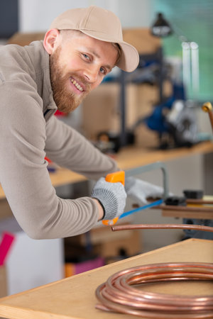 happy worker is cutting a cooper pipeの写真素材