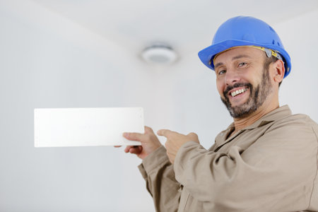 handsome repairman or builder in helmet working with boardの写真素材