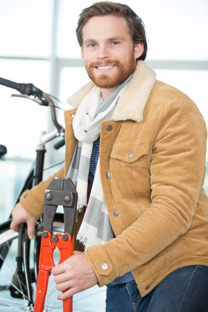 portrait of happy man unlocking bike lock in cityの写真素材