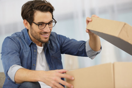 happy man opening parcel box at home