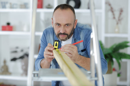 man measuring a wooden board at homeの写真素材