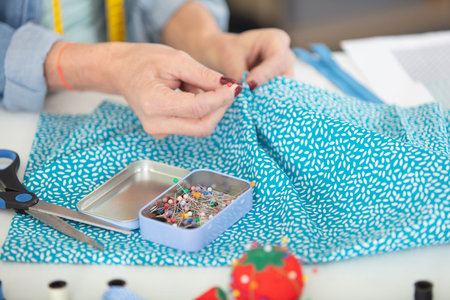 cropped view of female hands pinning fabric