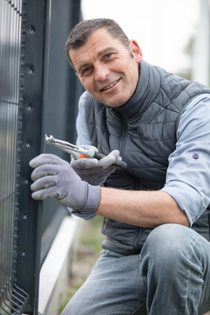 happy worker installing welded metal mesh fenceの写真素材