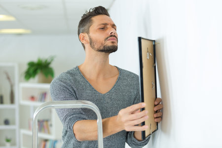 repairman putting picture frame onto wall