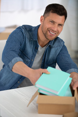man packing books into a cardboard box