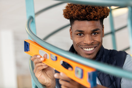 man holding spirit level against a railing