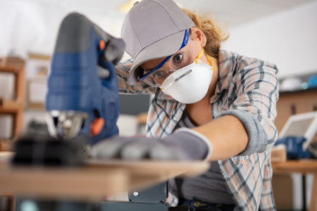 female carpenter using saw to cut wood
