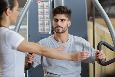 gym trainer showing right position to use gym machineの写真素材
