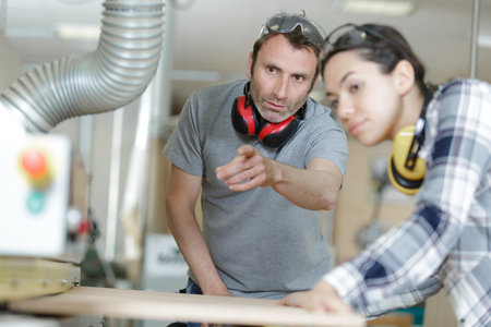 carpenter teaching apprentice how to cut wood