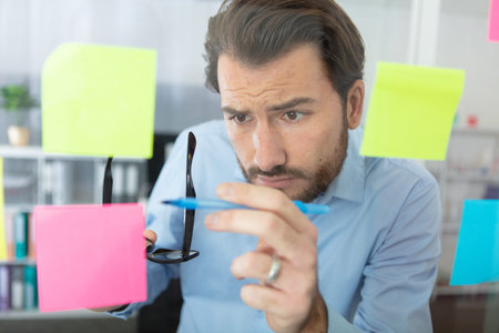 thoughtful man reading sticky notes in office