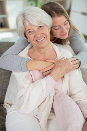 cheerful woman embracing her senior parent in kitchenの写真素材