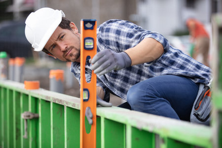 workman using spirit level on outdoor site