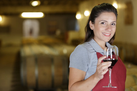 young woman posing with wine from wood in wine houseの写真素材