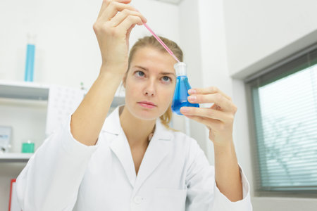 woman scientist adding liquid to test tube