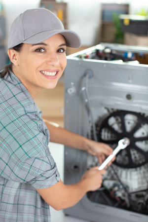 portrait of female service-agent repairing washing machineの写真素材