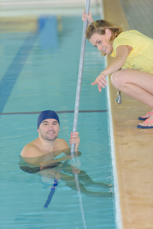 swimmer talking to his coach by poolside at leisure centerの写真素材