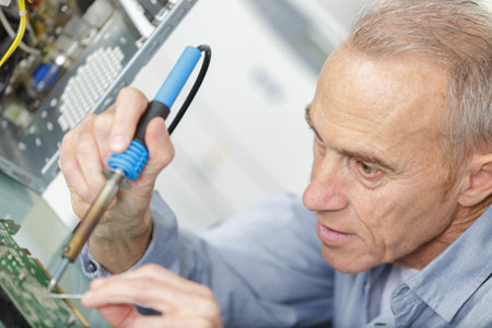 mature man soldering a wi-fi routerの写真素材
