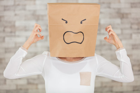 young woman in ecological paper bag on headの写真素材