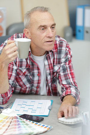mature man drinking coffee and arguing with opponentの写真素材