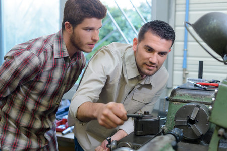 engineer adjusting machinery apprentice watching him