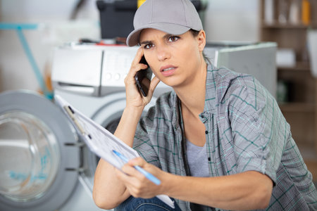 professional woman repairer fixing washing machineの写真素材