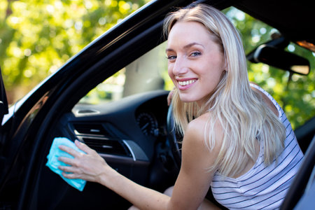 woman cleaning her car cockpit using spray and microfiber clothの写真素材
