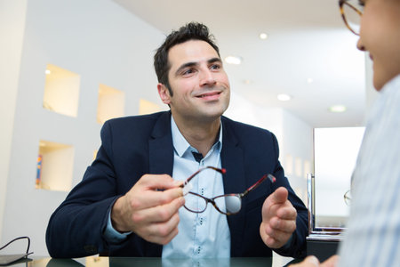 young woman choosing eye glasses in optician storeの写真素材