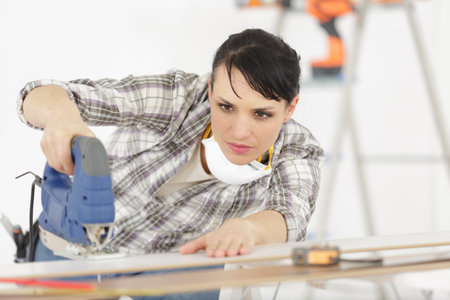 positive woman is cutting woodの写真素材