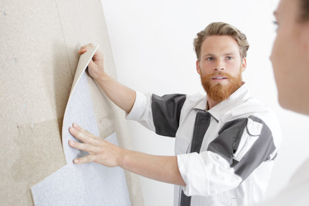 a handyman is fixing wallpaper