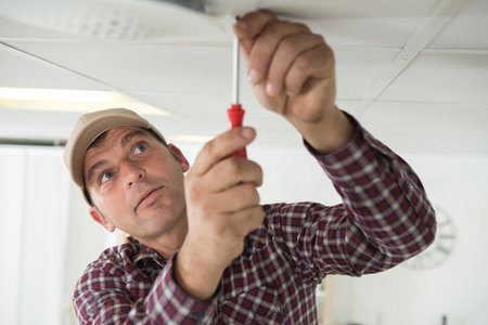 builder drives screws into ceilingの写真素材