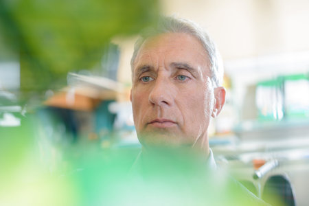 portrait of senior man shot through leaves for blurry effect