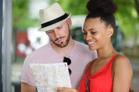 young couple looking at a tourist guide mapの写真素材