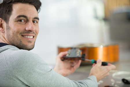 young handsome repairman repairing guitarの写真素材
