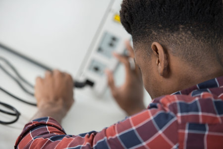 rear view of man inserting power cable into applianceの写真素材
