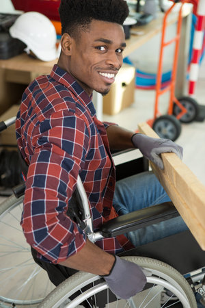 young man in wheelchair tries himself to fold his bookcaseの写真素材