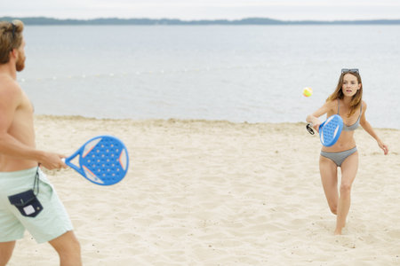 fit couple spending vacations playing beach sportsの写真素材