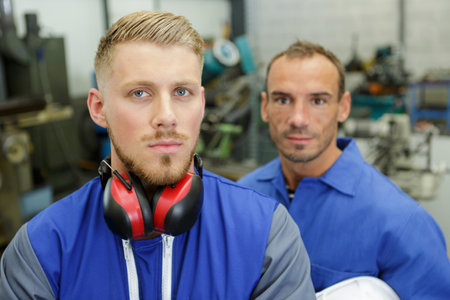 two mechanics working with different tools in a repair shopの写真素材
