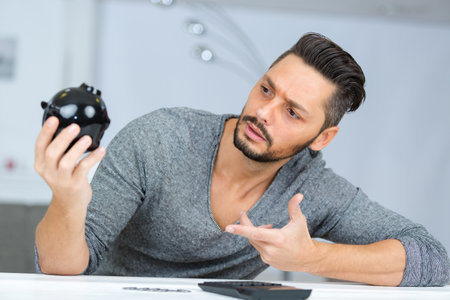 incredulous man questioning his piggy bankの写真素材