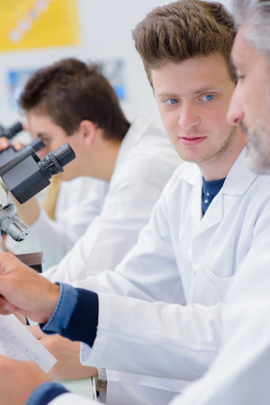 Man with microscope talking to teacher