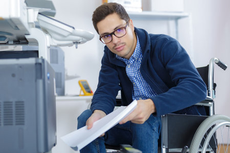 businessman in wheelchair using a printerの写真素材