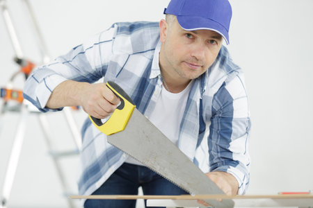 a man using handsaw in workshopの写真素材