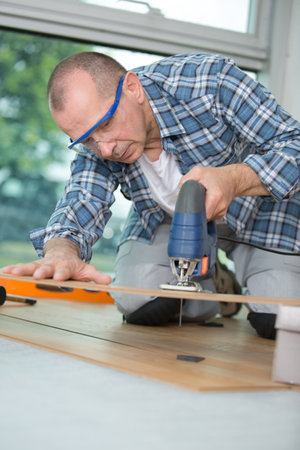 man cutting laminate board with jigsawの写真素材