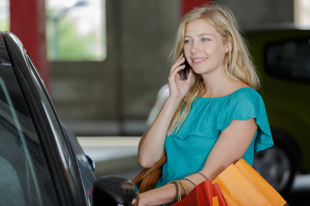 girl with shopping bags in car using cell phoneの写真素材