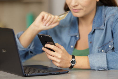 woman buying online payment on laptop reading credit card numberの写真素材