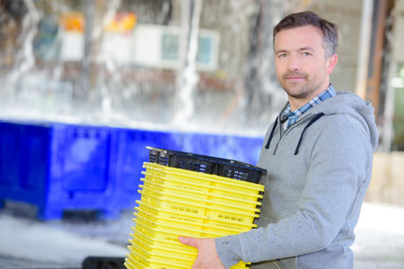 Portrait of man carrying stack of cratesの写真素材