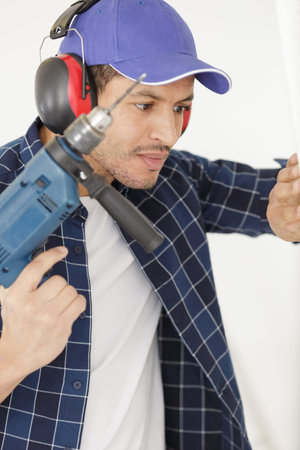man with power drill and earmuffs
