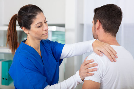 female chiropractic doctor examining injured shoulder of patientの写真素材